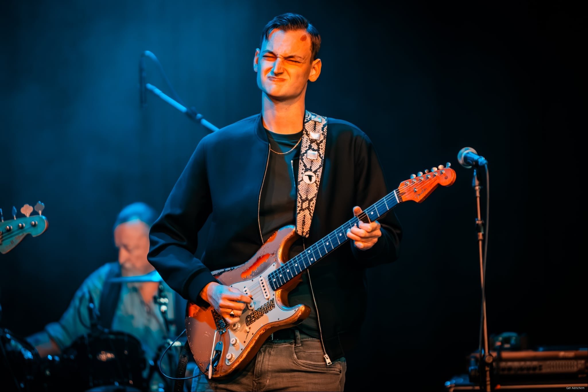 Gerbman on stage with sunburst relic Stratocaster under deep blue stage lighting, bassist visible — photo Ger Adrichem