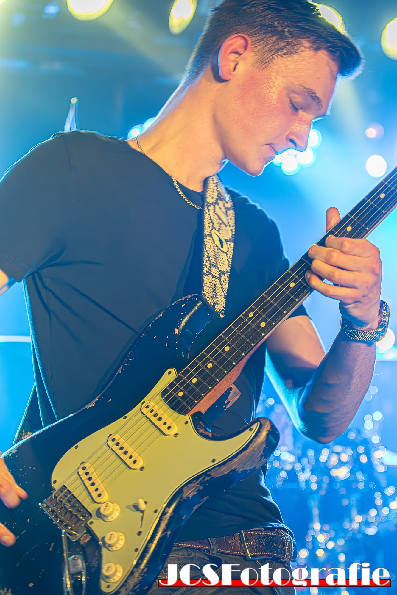 Gerbman close-up with black relic Stratocaster, blue stage lighting — JCSFotografie