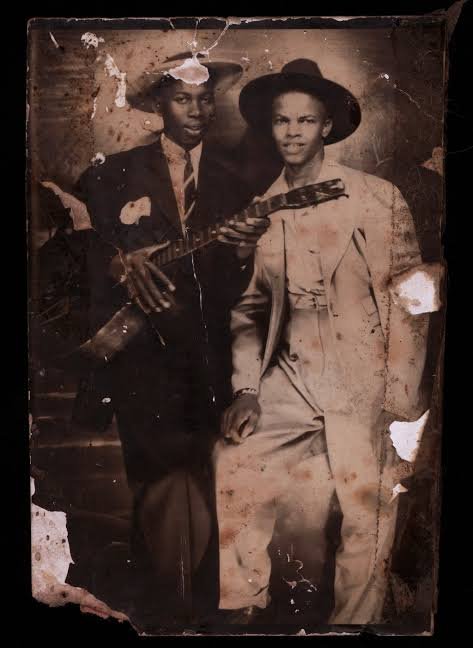 Weathered vintage photograph acquired by Zeke Schein, which he believes may depict Robert Johnson holding a guitar