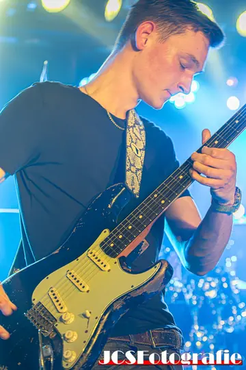 Gerbman in Nahaufnahme mit schwarzer Relic-Stratocaster, blaues Bühnenlicht — JCSFotografie